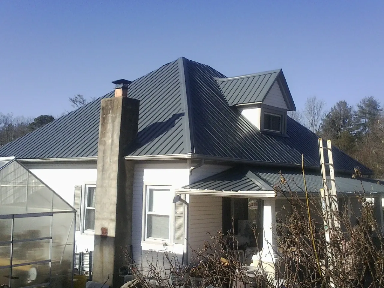 Dark blue standing seam metal roof on a white farmhouse with dormer — Slate & Tile Roof Repair by Roofing Brothers in Dupont