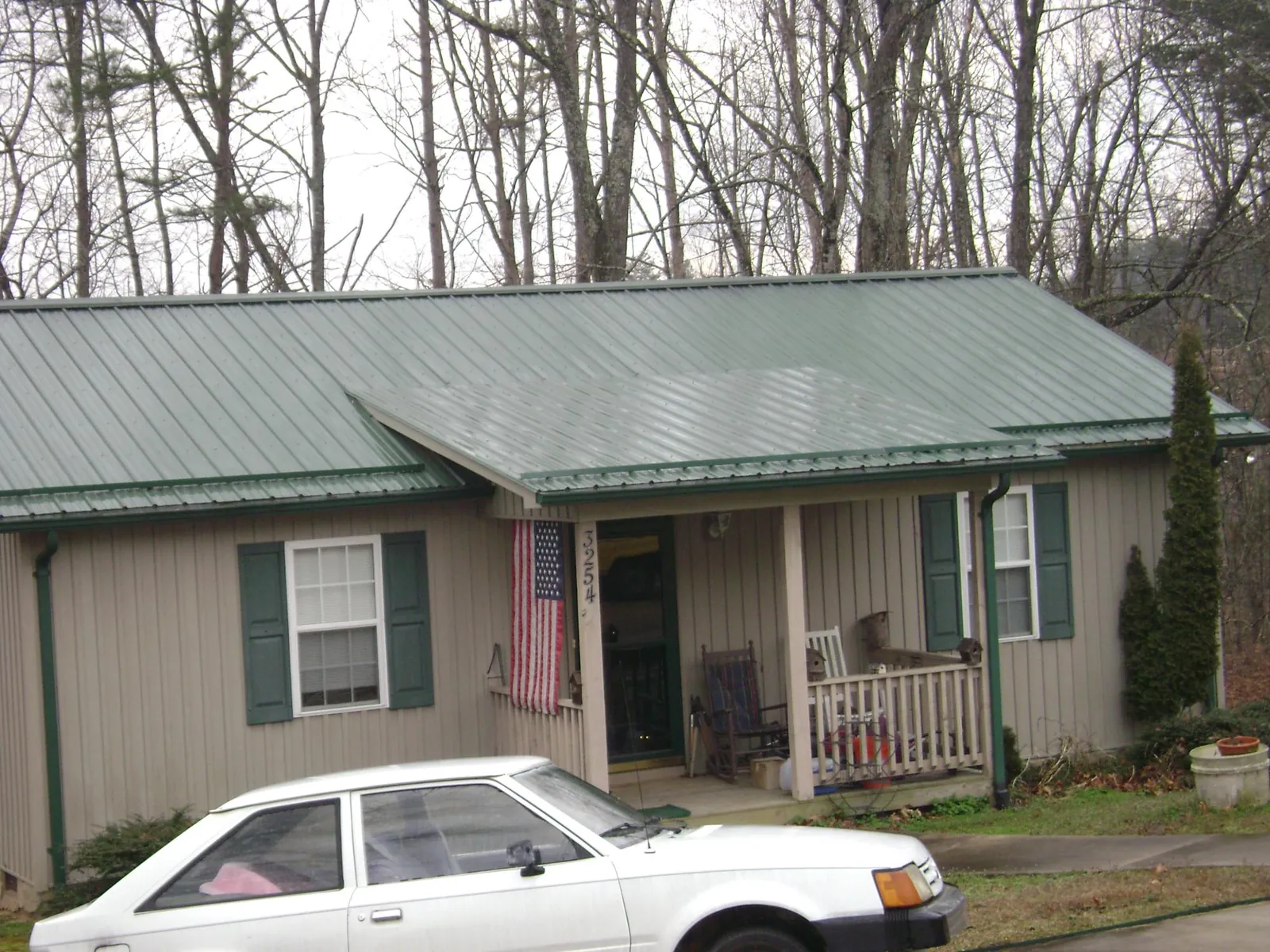 Green metal roof and front porch on a tan sided cottage in Dupont