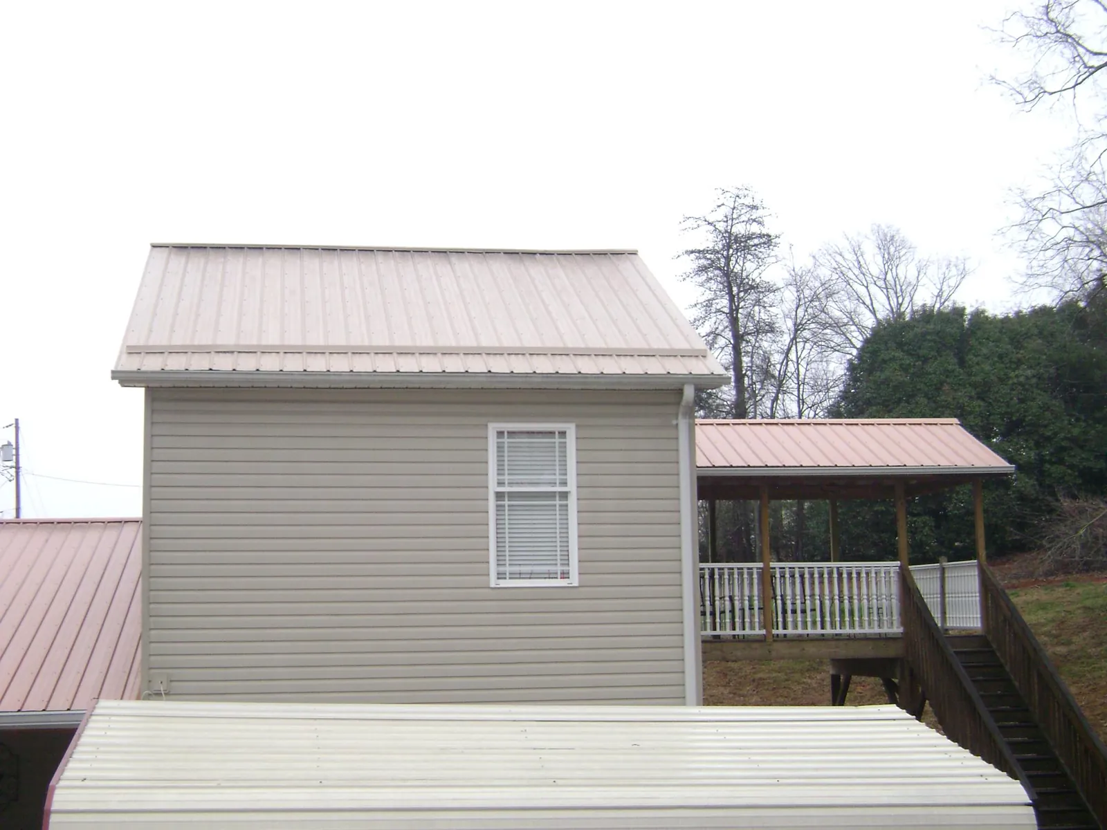 Tan metal roofs on a two story addition and attached porch, from a Roof Replacement job in Dupont